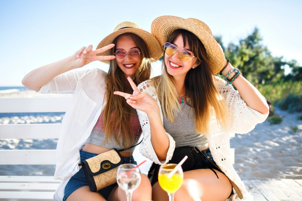 Outdoor portrait of company happy funny hipster girls going crazy on the beach cafe